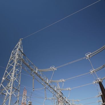 High-voltage transmission towers and cables set against a clear sky