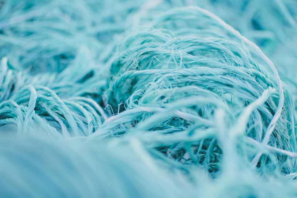Blue fiber and fishing net representing Hyosung’s world-first recycled yarn made from recycled fishing nets