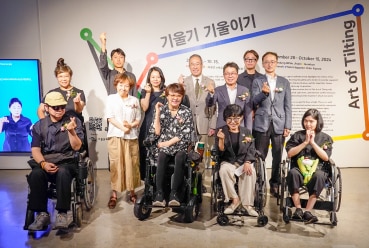 효성이 후원하는 장애예술가 지원 행사에서, 휠체어에 앉은 작가들과 관계자들이 함께 모여 손하트를 만들며 기념 촬영을 하는 모습