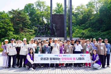 효성이 후원하는 국가유공자 나들이 행사에서, 참가자들이 '가을 찾아 떠나는 행복 여행' 현수막 뒤에서 머리 위로 하트를 만들며 기념 촬영을 하는 모습